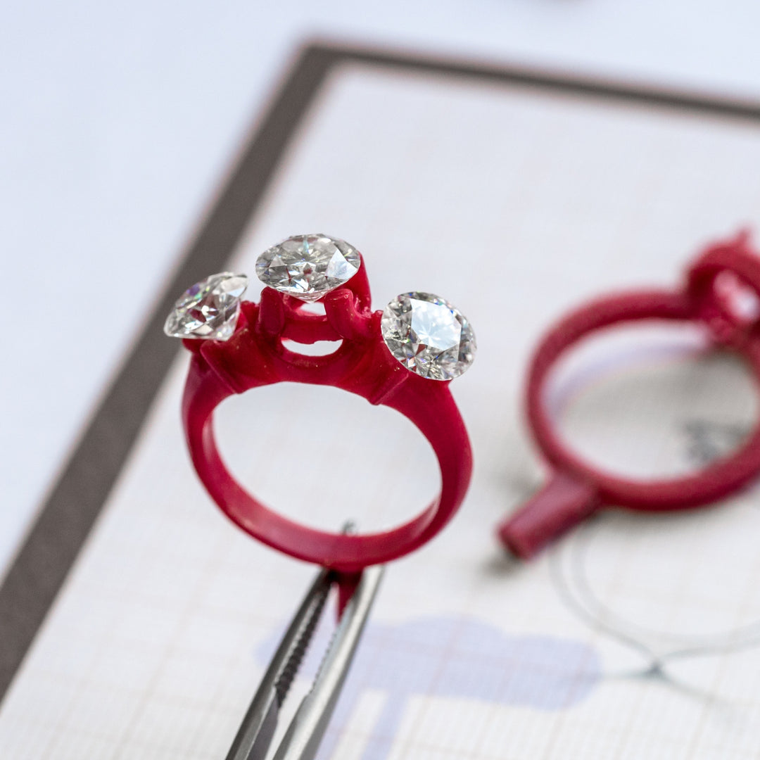 A close-up of three round diamonds on a red ring holder.