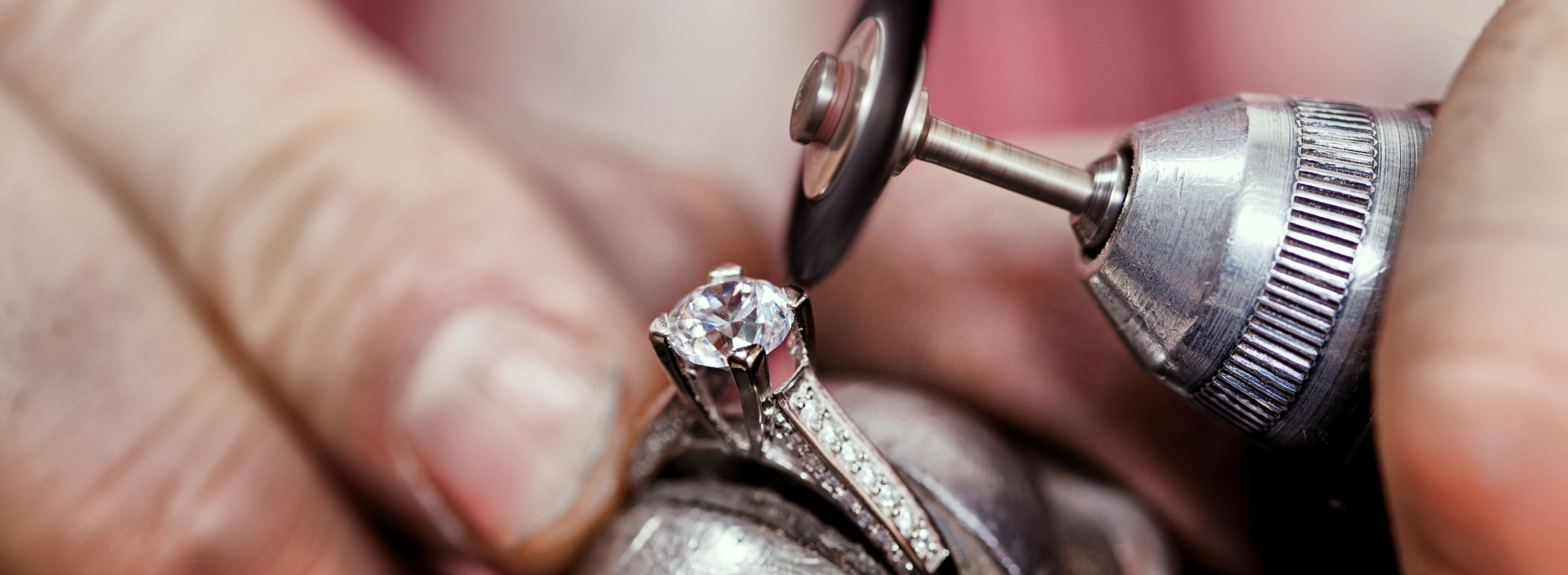 A close-up of a round-shaped diamond with a drill on the top right prong.
