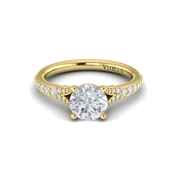 A front view of a yellow gold engagement ring is set against a white background. The engagement ring features a round center diamond, a split shank design, and a diamond-set band.