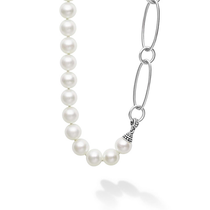 A close-up of a necklace against a white background. The necklace features a strand of pearls and alternating small and large white gold links.