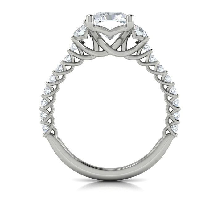 A top view of a white gold engagement ring is set against a white background. The engagement ring features a center emerald cut diamond flanked by two emerald cut side diamonds, an intricate woven setting, and a diamond-set band.