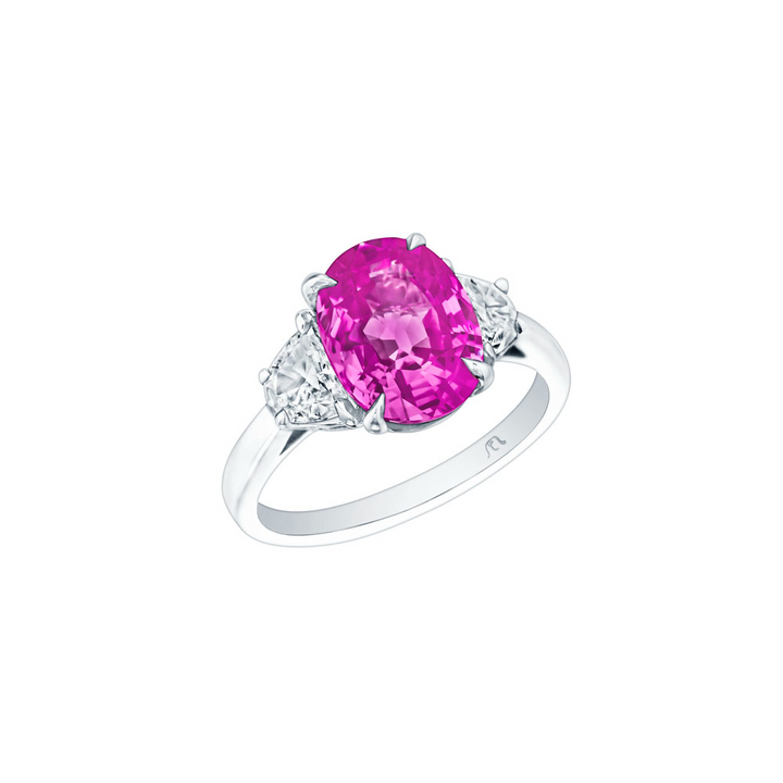 An angled view of a white gold diamond ring against a white background. The ring features a 3-stone design with an oval-cut pink sapphire at the center, framed by two perfectly matched half-moon diamond side stones.