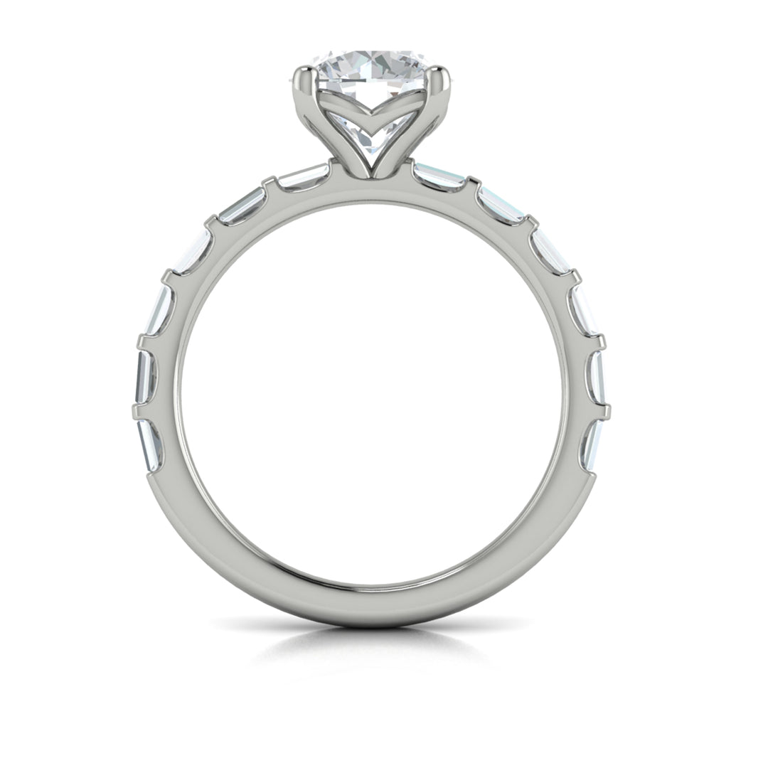 A top view of a white gold engagement ring is set against a white background. The engagement ring features a center round cut diamond, an Art Deco design, and a streamlined band of bar-set baguette diamonds.