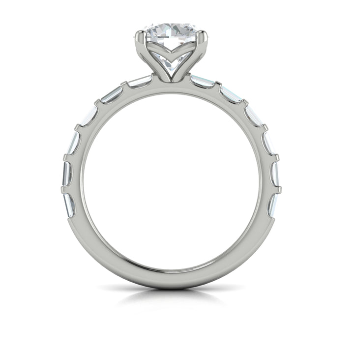 A top view of a white gold engagement ring is set against a white background. The engagement ring features a center round cut diamond, an Art Deco design, and a streamlined band of bar-set baguette diamonds.
