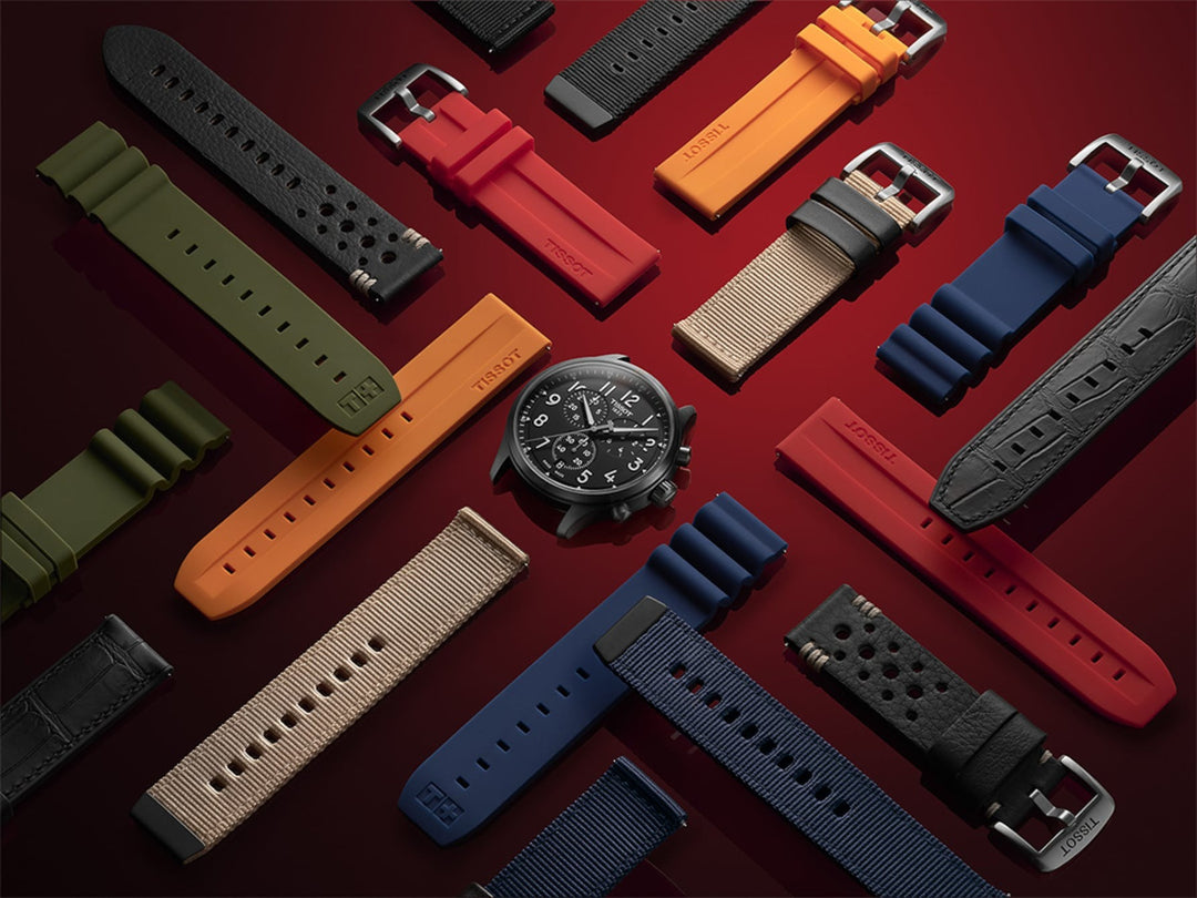 A scattered photo of a black Tissot dial in the middle and different color fabric, rubber, and leather straps across a red background.
