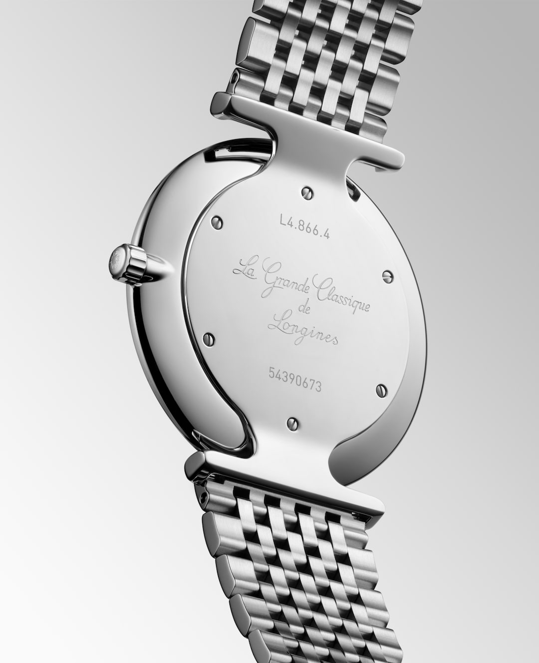 A Longines watch is displayed in the middle, angled to the right, showcasing the back of the dial on a white background. The back of the watch has La Grande Classique de Longines engraved in the middle of the dial and L4.866.4 on the top.