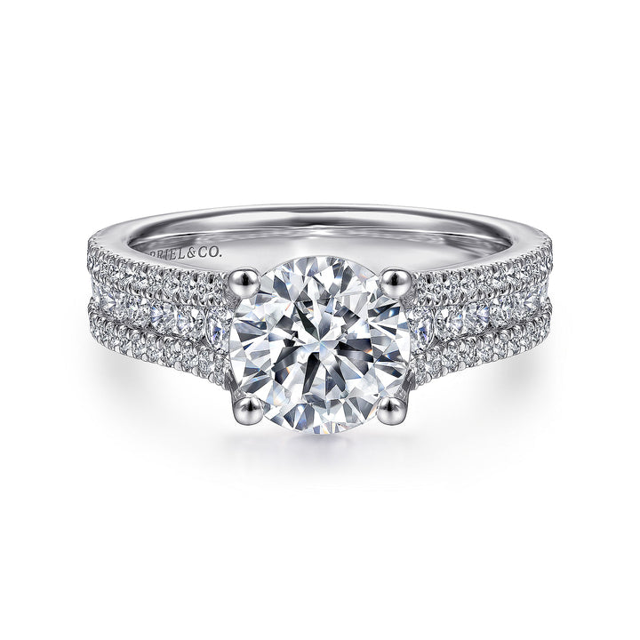 A white gold ring lies flat against a white background. It features a round-cut diamond set in the center and three rows of diamond set bands.