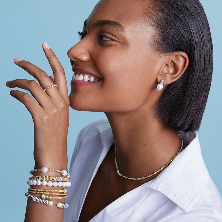 A woman is wearing a bracelet featuring a single strand of cultured freshwater pearls