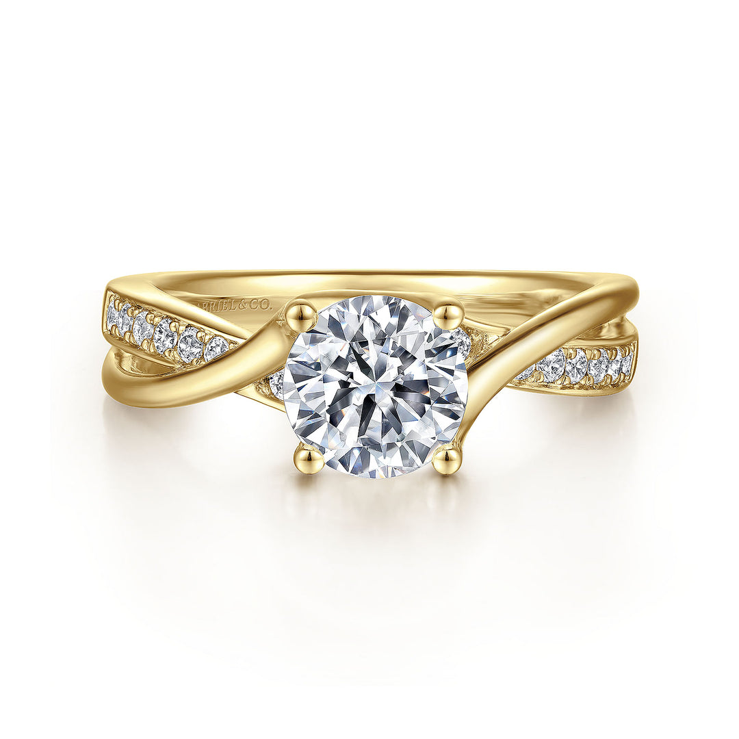 A yellow-gold ring lies flat against a white background. It features a round-cut diamond set in the center with a twisted design band.