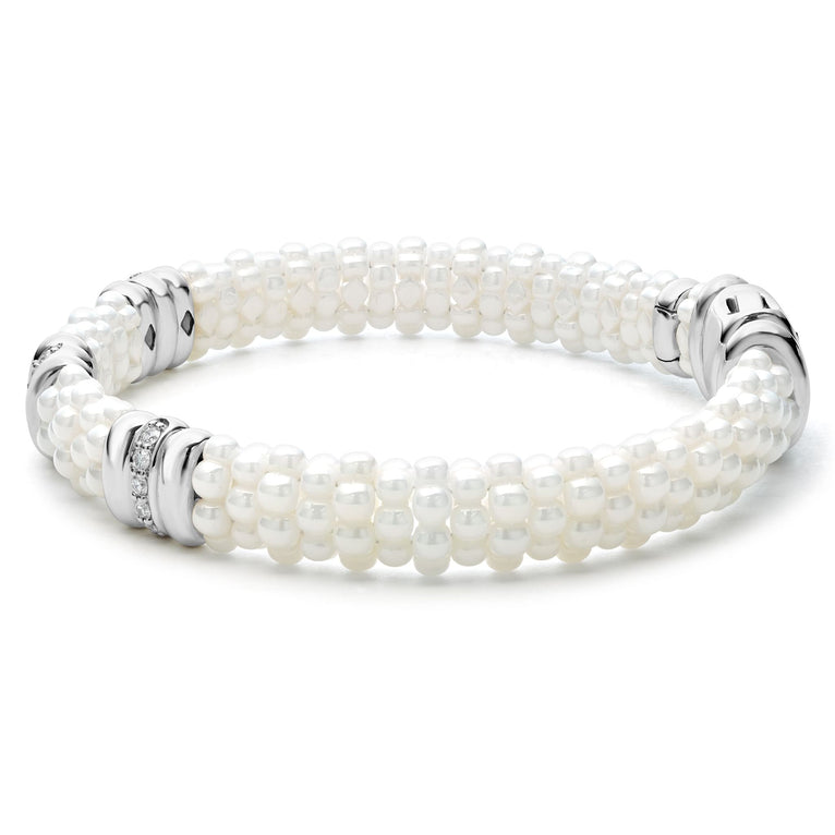 A side-view of a sterling silver bracelet in the middle of a white background featuring three diamond stations, white ceramic caviar beading, and sterling silver stations