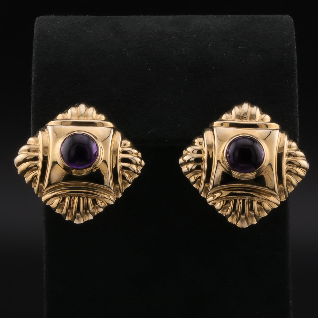 Yellow-gold square-shaped earrings with a vibrant central amethyst stone against a black background.