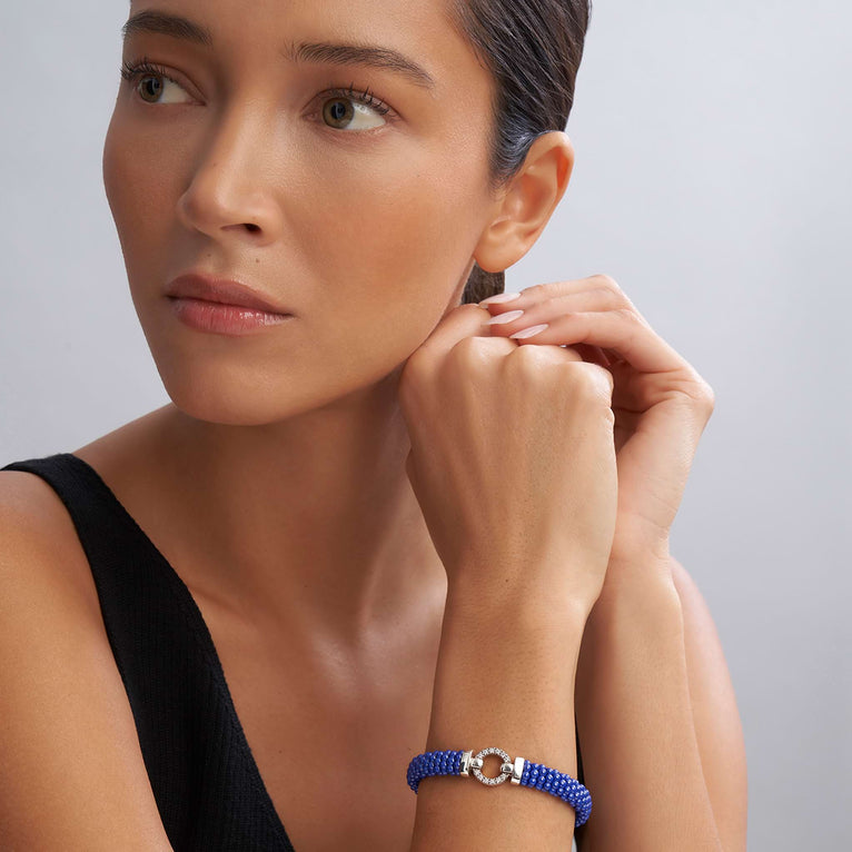 A woman wearing a sterling silver bracelet in the middle of a white background features a diamond circle motif and ultramarine ceramic caviar beading.