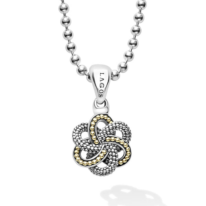 A close-up of a pendant necklace featuring a caviar beaded love knot pendant finished on a ball chain necklace.