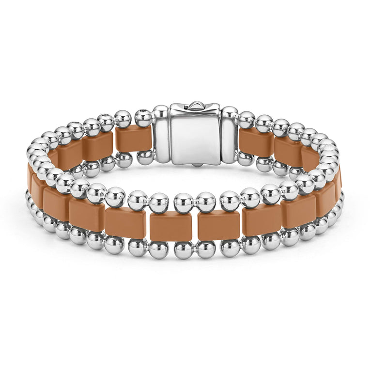 A stainless steel bracelet in the middle of a white background featuring matte tan ceramic and caviar beading.