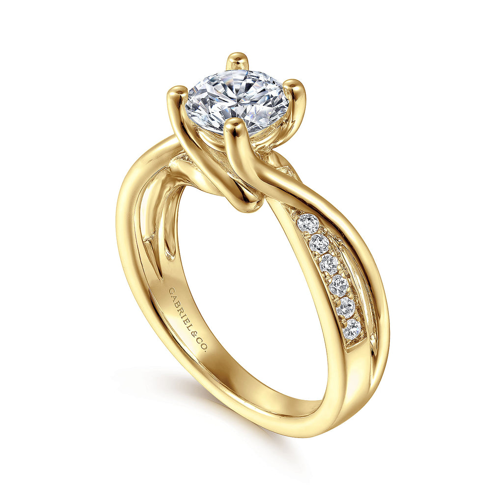 A close-up of a ring made of yellow gold, angled to the left against a white background. It features a round-cut diamond set in the center with a twisted design band.