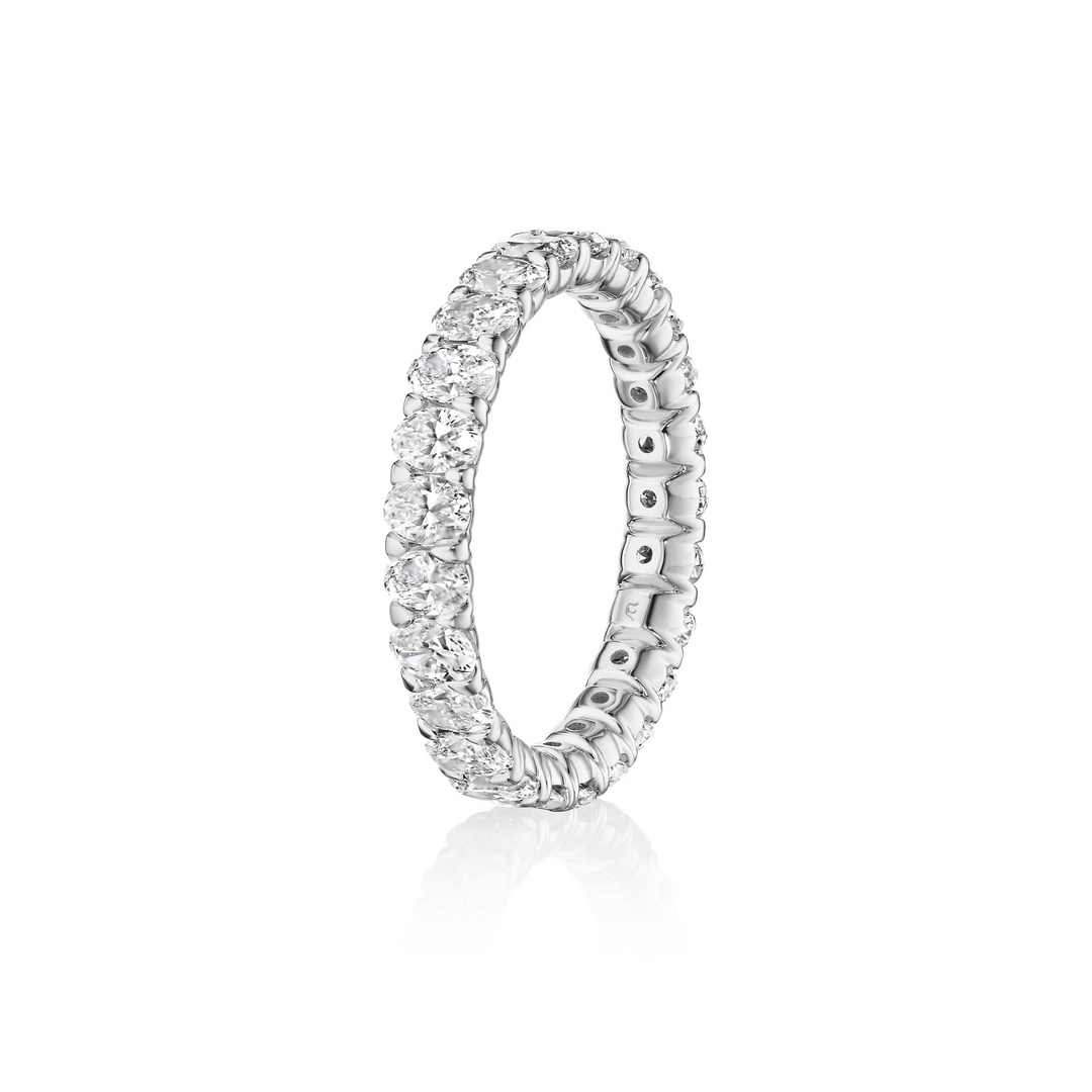 A close-up photo side view tilted to the left shows a white gold woman's wedding band with oval-cut diamonds and the inside of the band on a white background.