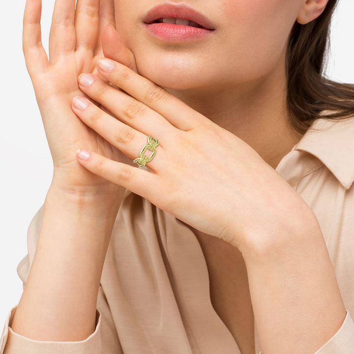 A woman wearing an 18K gold oval link ring features caviar beading and fluting elements.