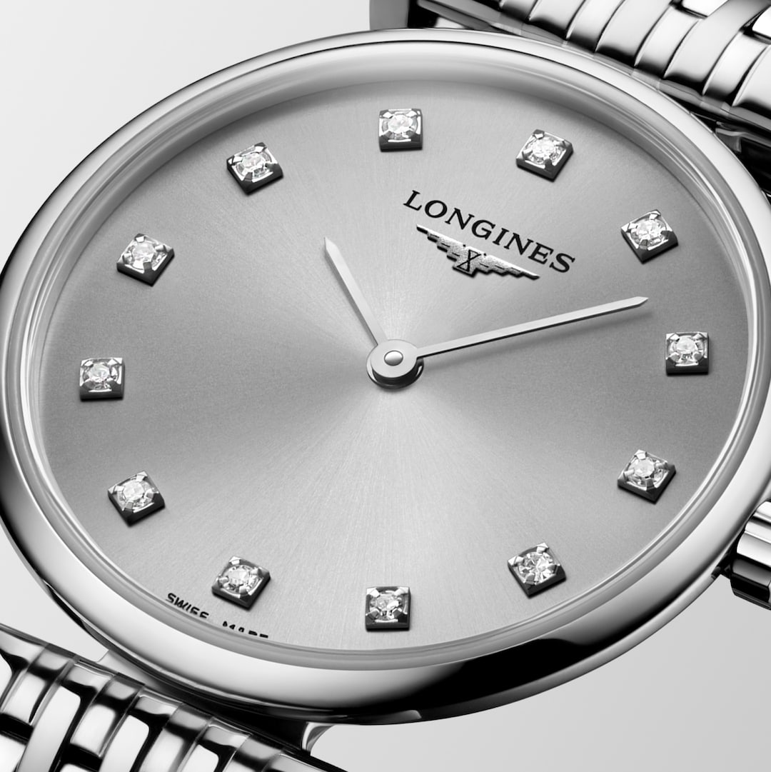 This is a close-up of a Longies watch angled to the right, showcasing the dial with a white background. The watch features a silver diamond-set dial, silver hands and markers, a stainless steel bezel, and a stainless steel bracelet.