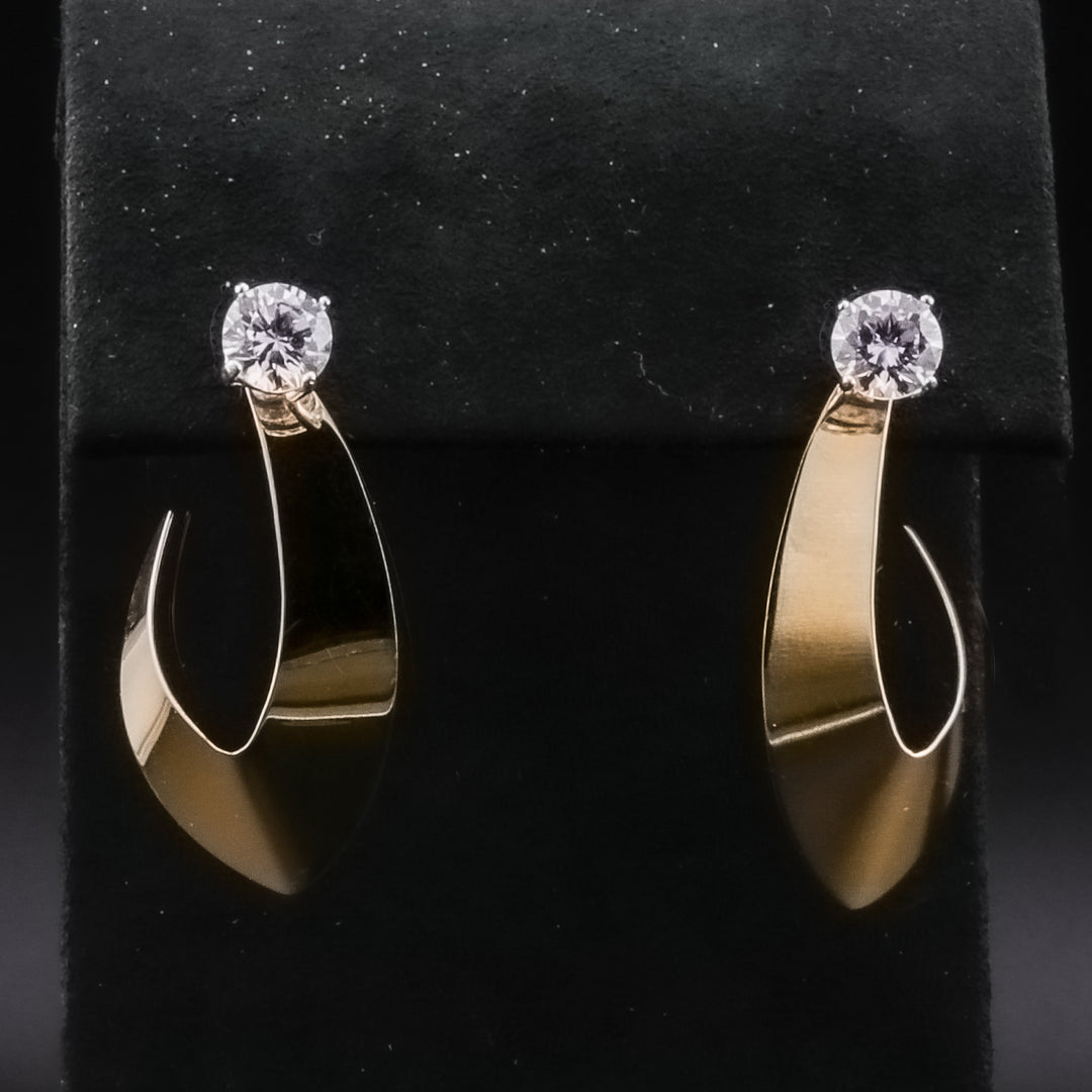 A pair of hoop earrings with a swoop jacket design and a diamond set at the top against a black background.