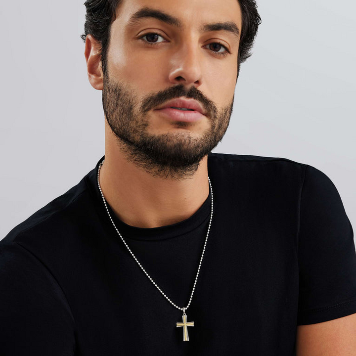 A man wearing a two-tone caviar beaded cross amulet with a chain necklace