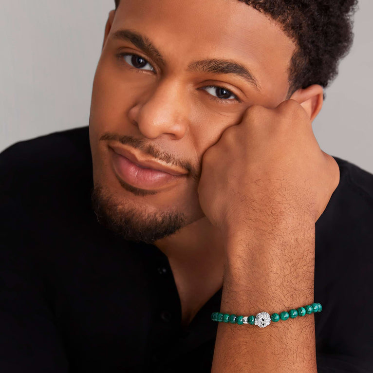 A man is wearing a sterling silver bracelet featuring a Malachite gemstone beaded bracelet with a silver Caviar skull.