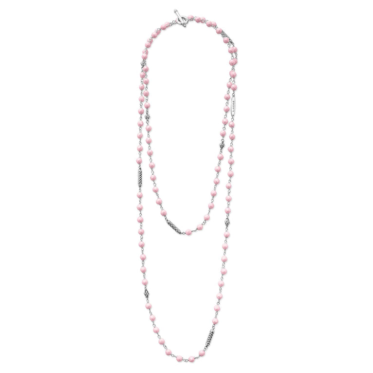 A sterling silver and ceramic beaded necklace in the middle of a white background featuring Pink ceramic and silver Caviar beading.