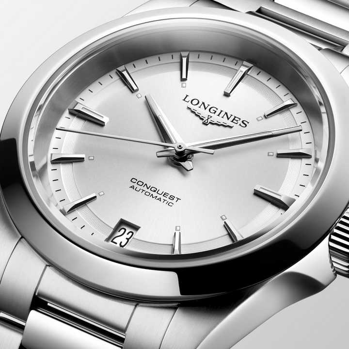 This is a close-up of a Longies watch angled to the right, showcasing the dial with a white background. It features a silver dial, silver hands and markers, a stainless steel bezel, and a stainless steel bracelet.