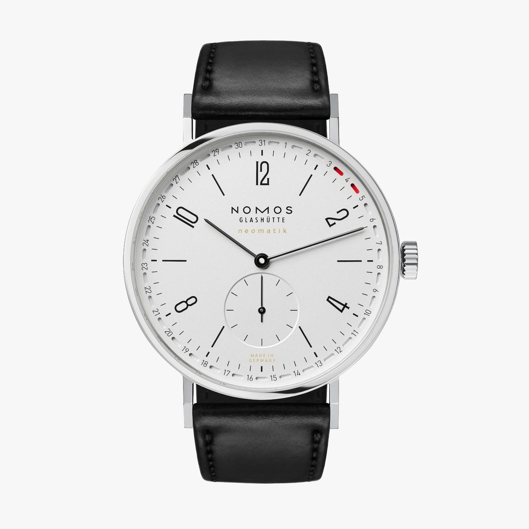 A Nomos Glashutte watch stands straight against a white background. It features a white dial, black hands and markers, a stainless steel bezel, and a black leather strap.