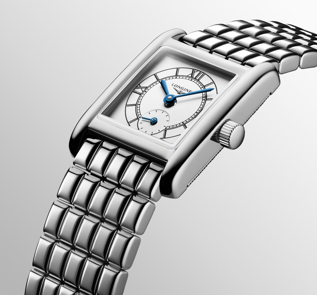 A Longines watch is displayed in the middle, angled to the right on a white background. The rectangular-shaped watch features a white dial, blue hands, black markers, a stainless steel bezel, and a stainless steel bracelet.