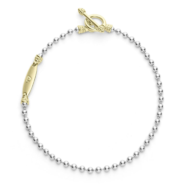 A sterling silver link bracelet in the middle of a white background featuring ball chain bracelet finished with a gold toggle clasp