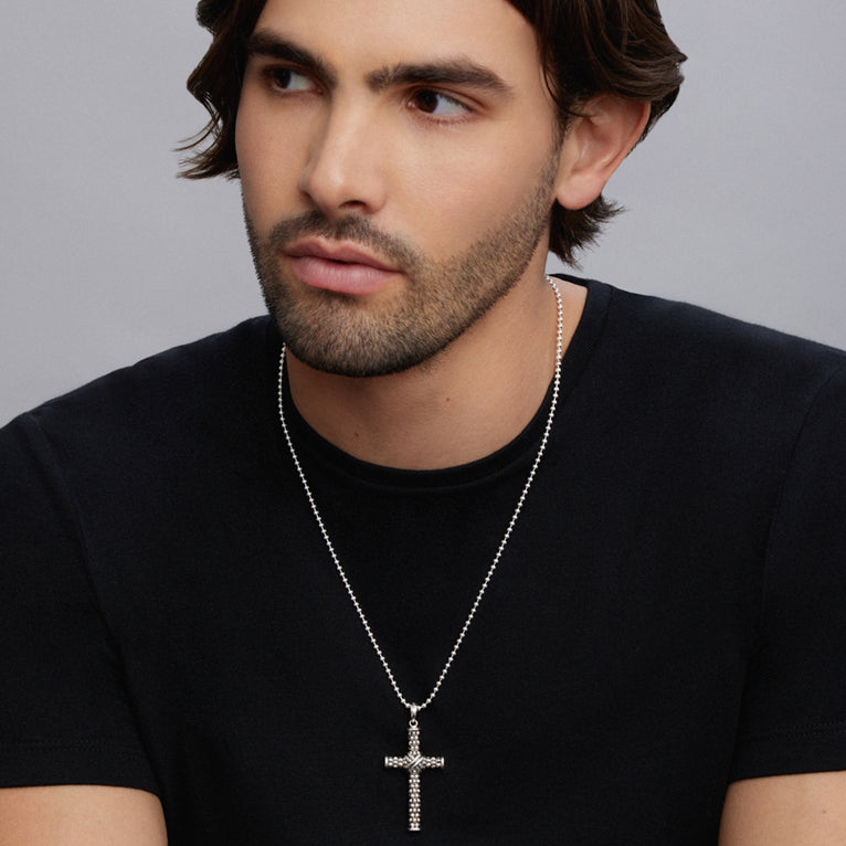 A man wearing a black shirt and a Caviar Beaded X Cross Amulet with a chain necklace