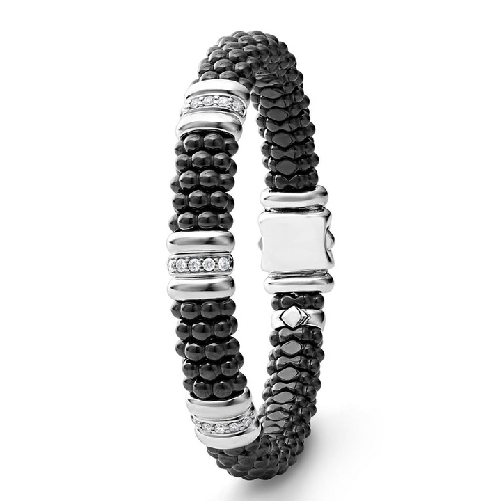 A sterling silver bracelet laid vertically in the middle of a white background featuring three diamond stations, black ceramic caviar beading, and sterling silver stations