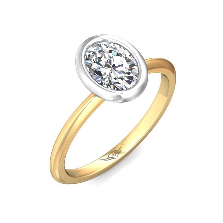 A close-up view of the Bezel Set Engagement Ring, made of yellow gold. The ring is angled against a white background to the right. It features an oval-cut diamond set in the center with a white gold bezel setting. Showing the "Martin Flyer" inscription is visible inside the band