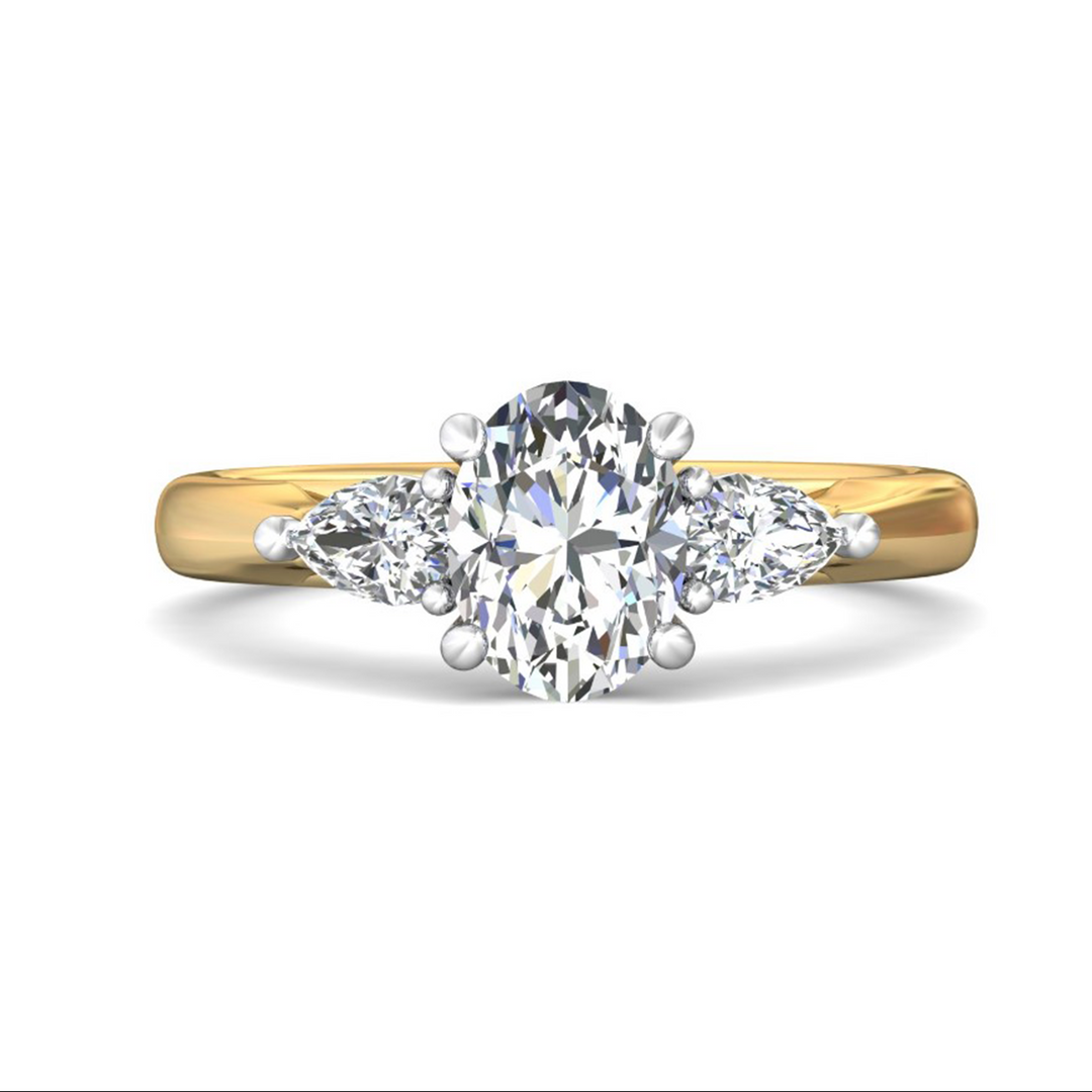 The Pear Side Stones Engagement Ring, made of yellow gold, lies flat against a white background. It features an oval-cut diamond set in the center with pear-shaped side diamonds