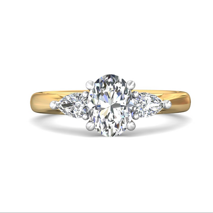 The Pear Side Stones Engagement Ring, made of yellow gold, lies flat against a white background. It features an oval-cut diamond set in the center with pear-shaped side diamonds