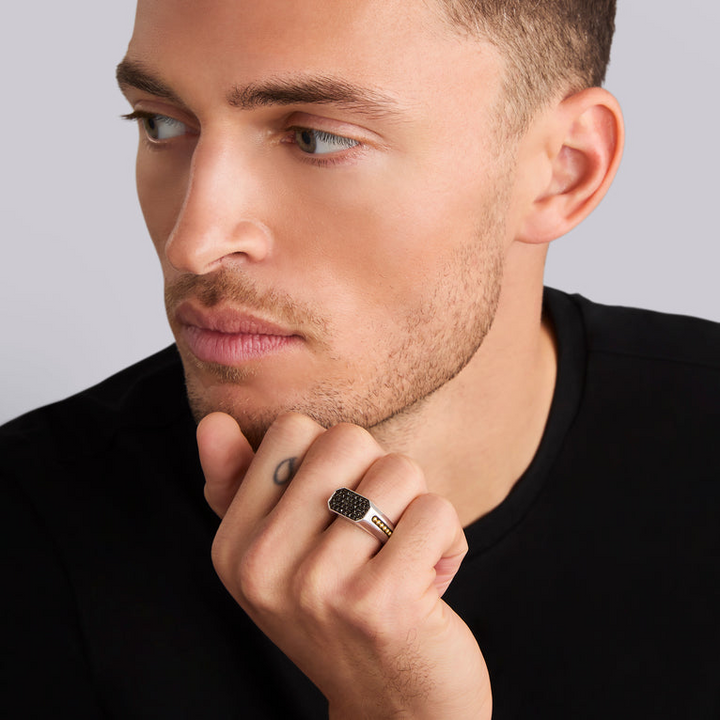 A man wearing a Sterling Silver & 18K Gold ring in the middle of a white background, featuring black diamonds accented by sterling silver and 18K gold Caviar beading