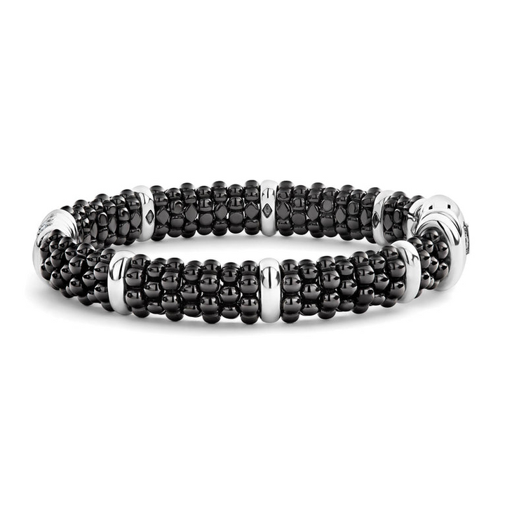 A side-view of a sterling silver bracelet in the middle of a white background featuring three diamond stations, black ceramic caviar beading, and sterling silver stations