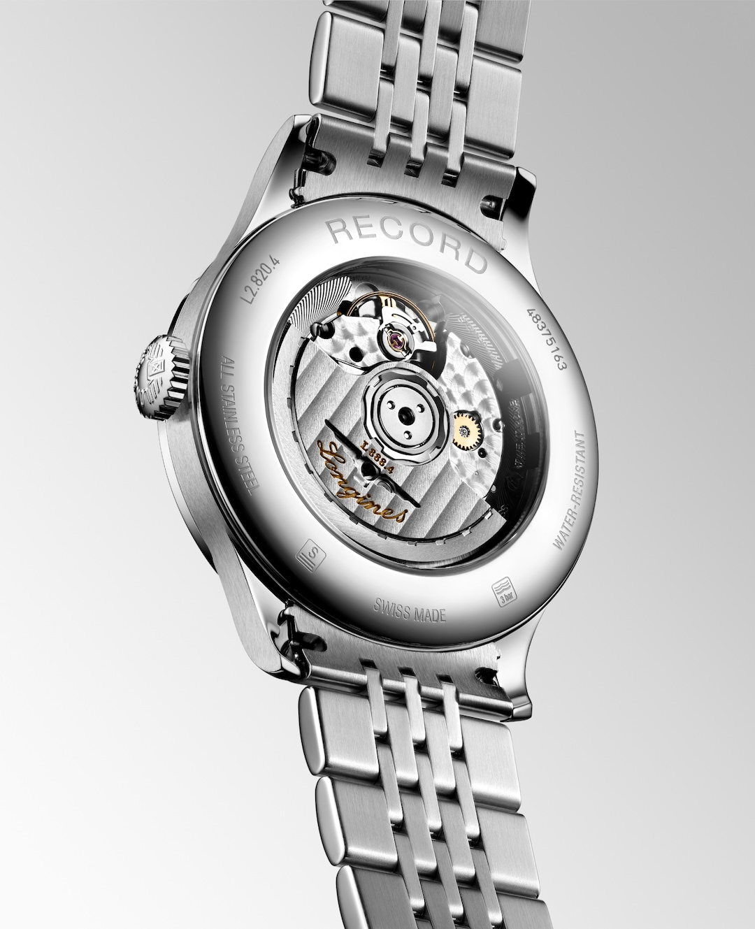 The back of a Longines watch is angled to the right, highlighting the case with an open heart design on the back and strap details. 