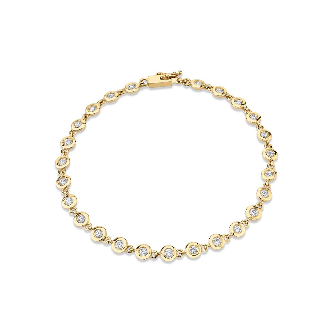 A yellow-gold bracelet lying flat against a white background. The bracelet features a row of bezel-set stones.