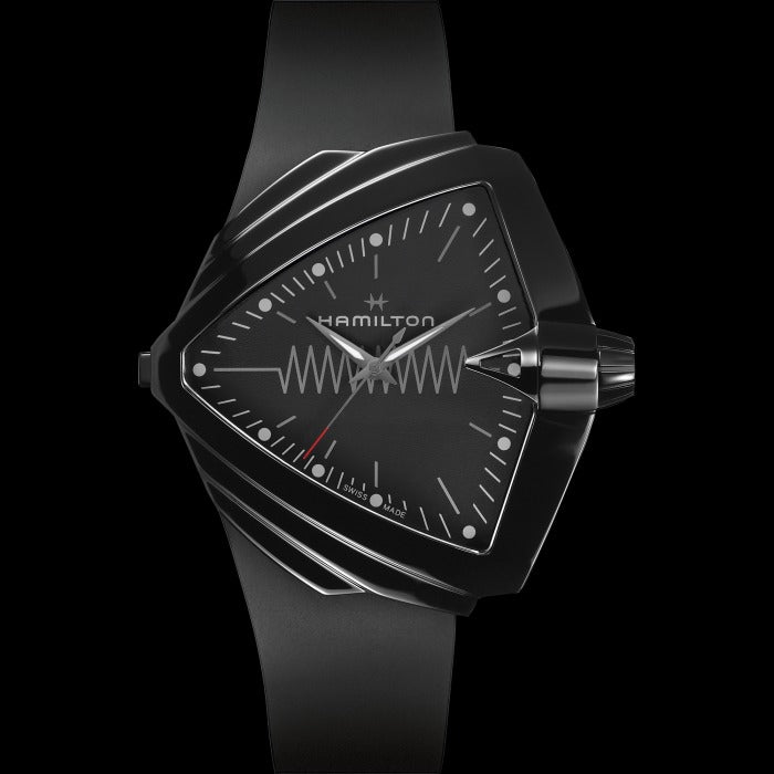 A Hamilton triangular-shaped watch is laid out against a black background. It features a black dial, white hands and markers, a steel PVD black coating case, a black bezel, a steel crown, and a black rubber strap.