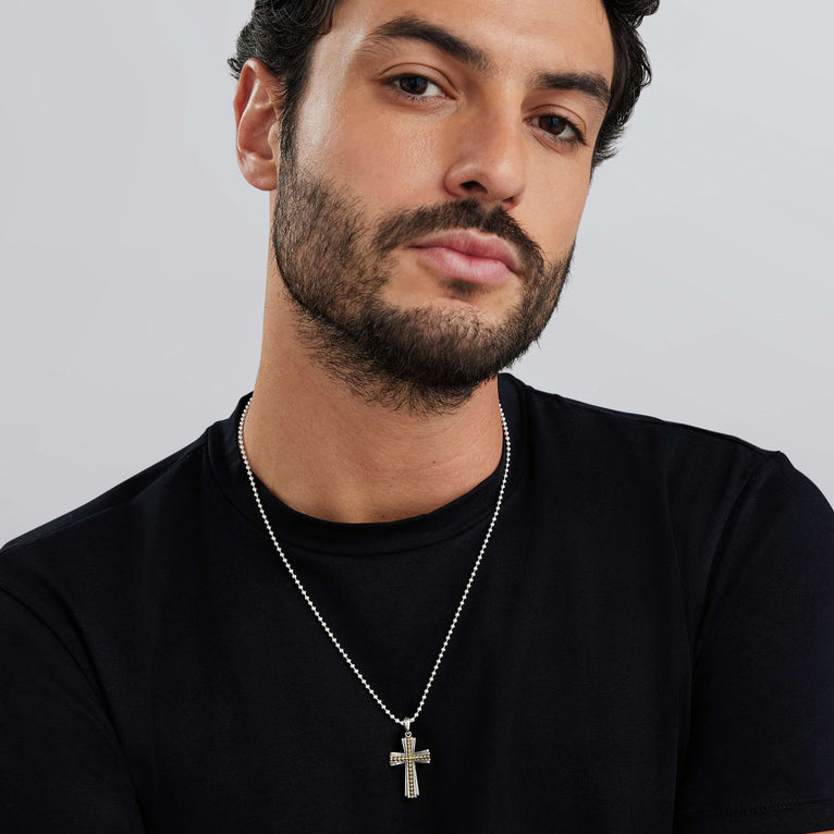 A man wearing a two-tone caviar beaded cross amulet with a chain necklace