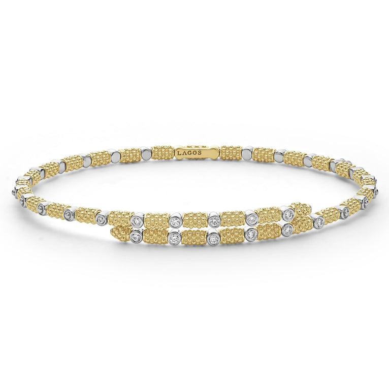 An 18K gold cuff bracelet laying in the middle with a white background, featuring caviar beading and diamonds