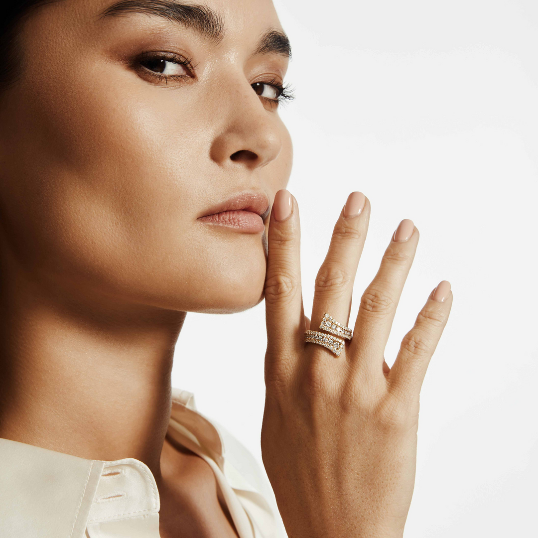 A close-up of a woman wearing a yellow gold ring with a unique band with three rows of pave-set diamonds