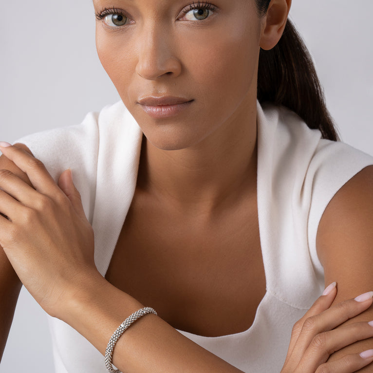 A woman is wearing a Sterling silver bracelet featuring seven sterling silver stations and caviar beading.