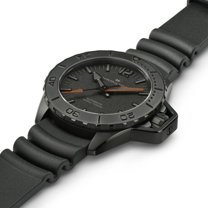 A Hamilton watch is laid out tilted to the right against a white background. It features a black dial, white hands and markers, a PVD black coating steel case, a steel bezel, a steel crown, and a rubber strap.