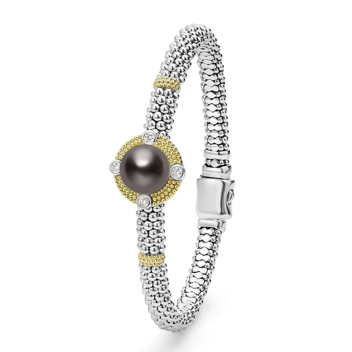 A Sterling silver & 18k gold bracelet laid vertically in the middle of a white background featuring a Tahitian black pearl surrounded by diamonds, gold stations, and caviar beading.