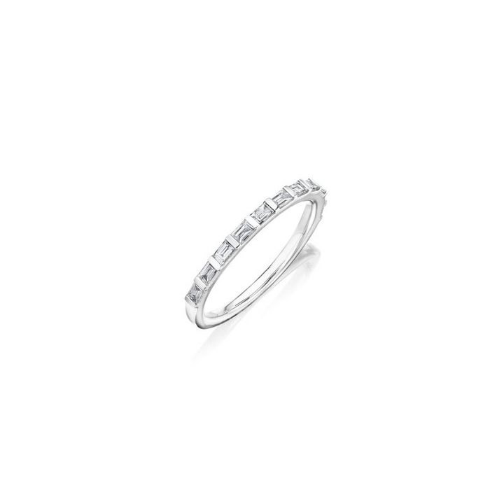 This is a close-up of a white gold ring angled to the left. It shows the inside of the band against a white background. It features a diamond set band with baguette detailing.