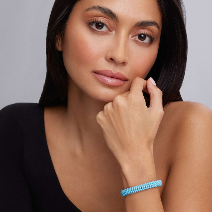 A woman is wearing the sterling silver beaded bracelet featuring light blue ceramic caviar beading and a sterling silver box clasp.