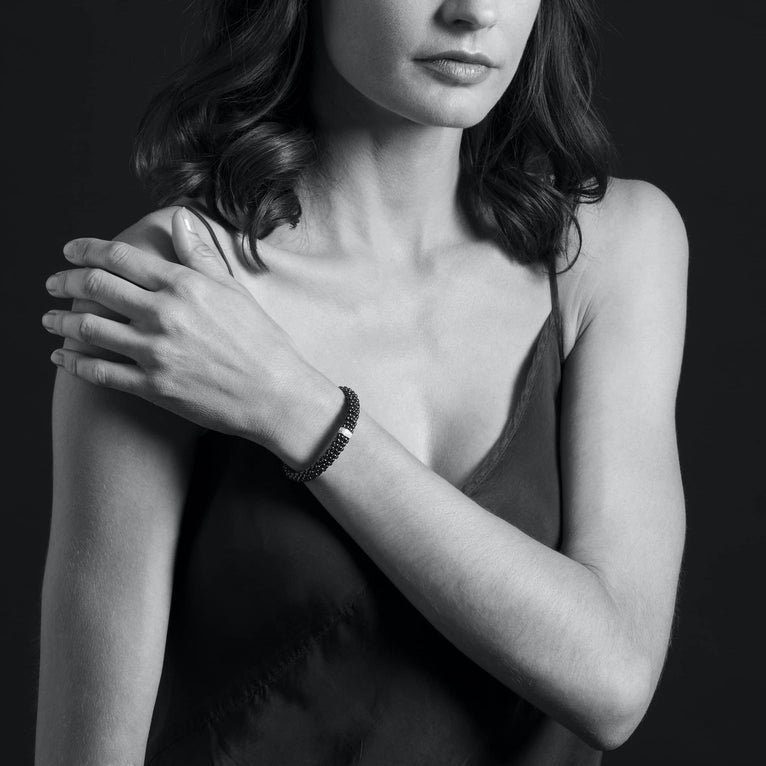 A woman is wearing a sterling silver bracelet featuring diamonds is set in silver and surrounded by black ceramic Caviar beading.