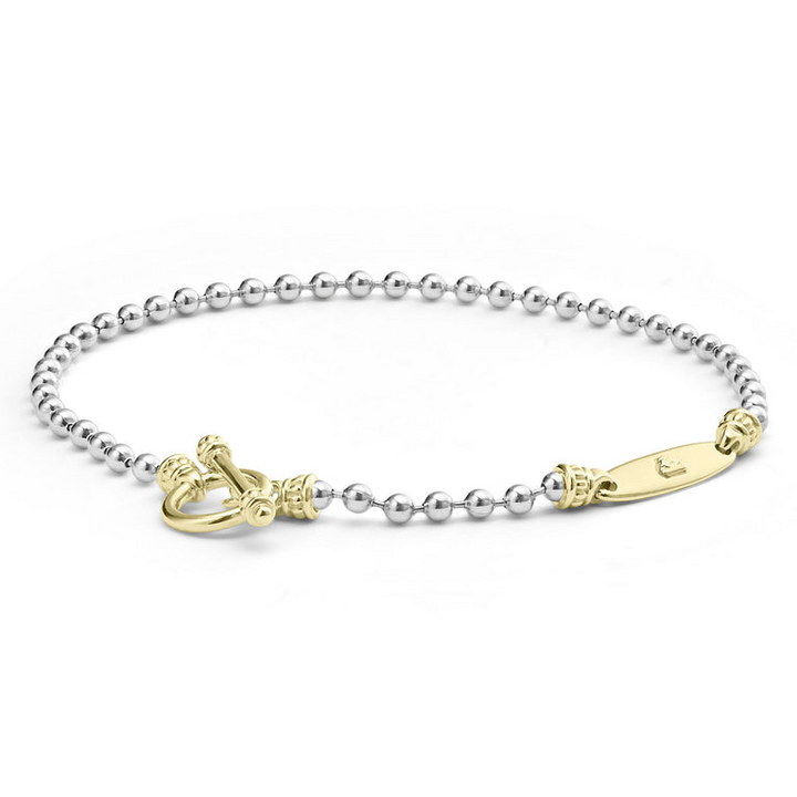 A sterling silver link bracelet angled in the middle of a white background featuring ball chain bracelet finished with a gold toggle clasp